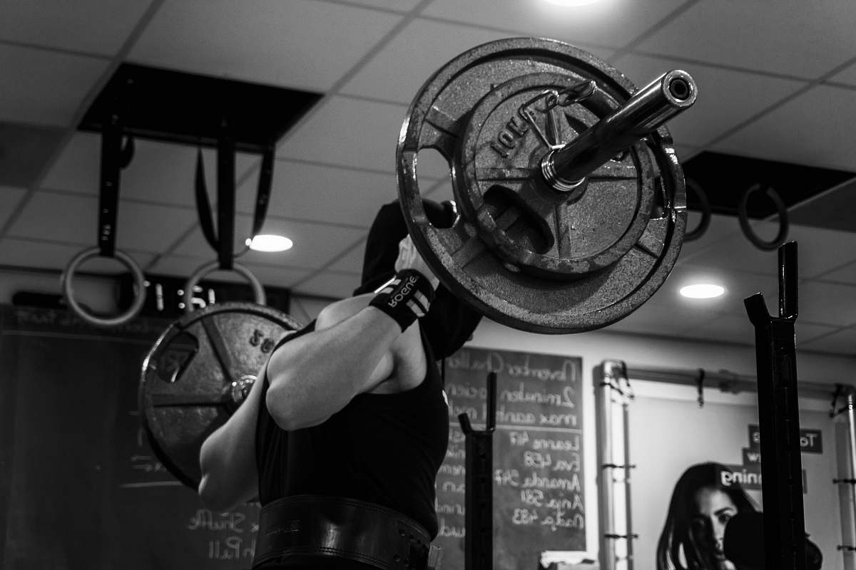working out grayscale photo of man lifting barbell black-and-white